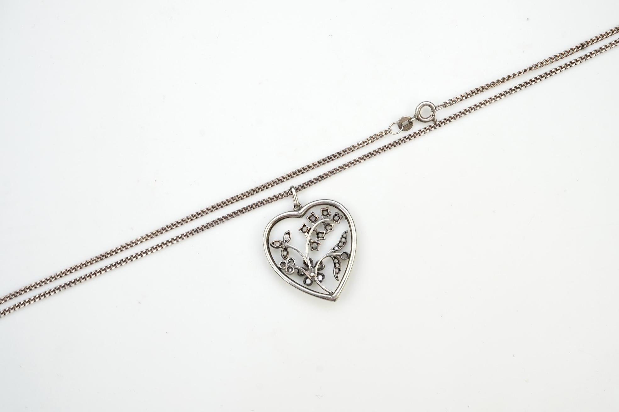 A diamond pendant, designed as a spray of flowers in a heart-shaped frame, set with rose-cut diamonds and a circular-cut ruby, to a later silver chain, pendant 3.1cm, chain length 44cm